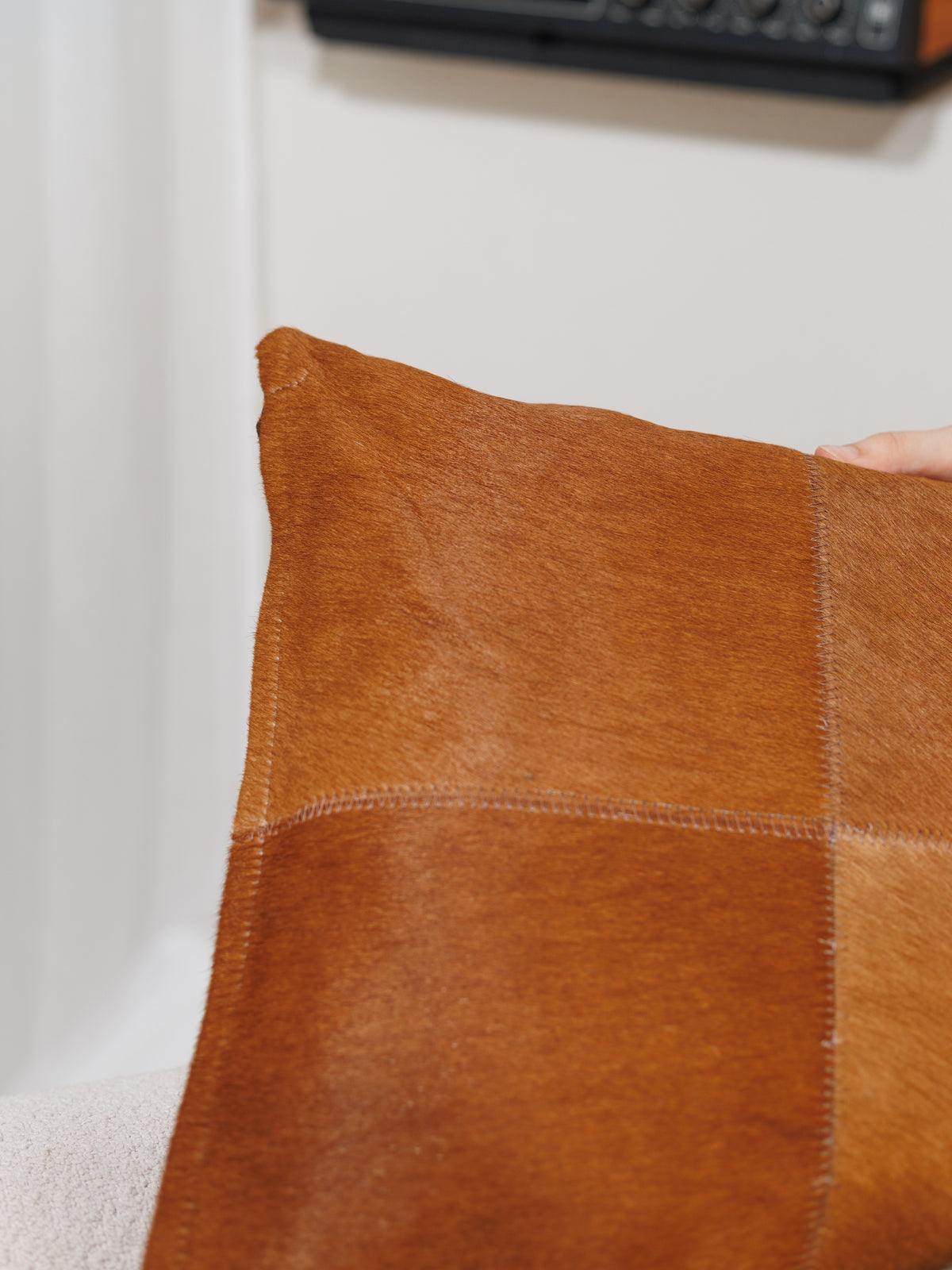 Housse de coussin en peau de vache caramel, gros plan sur le poil et les coutures