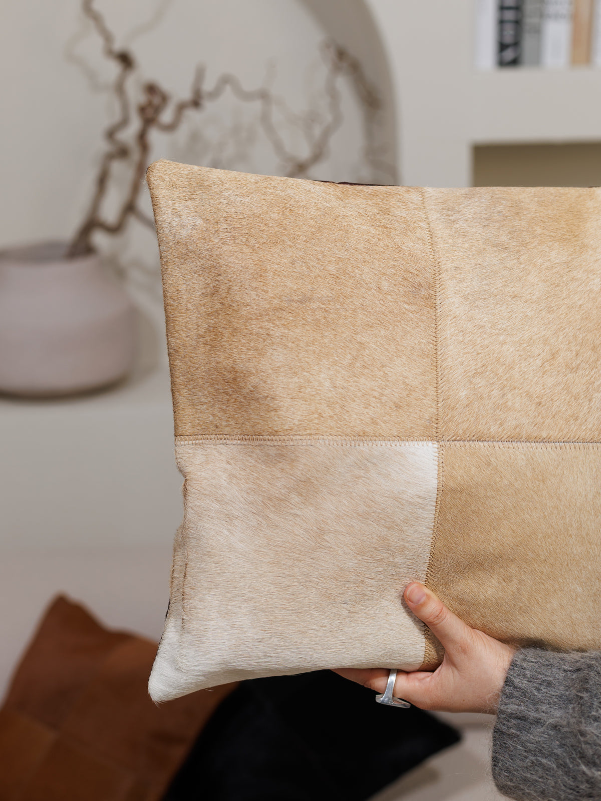 Housse de coussin en peau de vache caramel, tenue en main