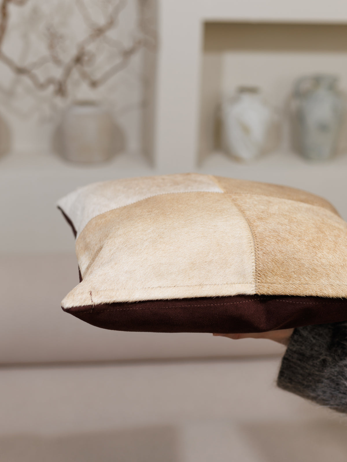 Housse de coussin en peau de vache caramel vue de côté, dos en tissu brun foncé