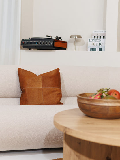 Housse de coussin en peau de vache caramel, ton plus soutenu, sur un canapé clair