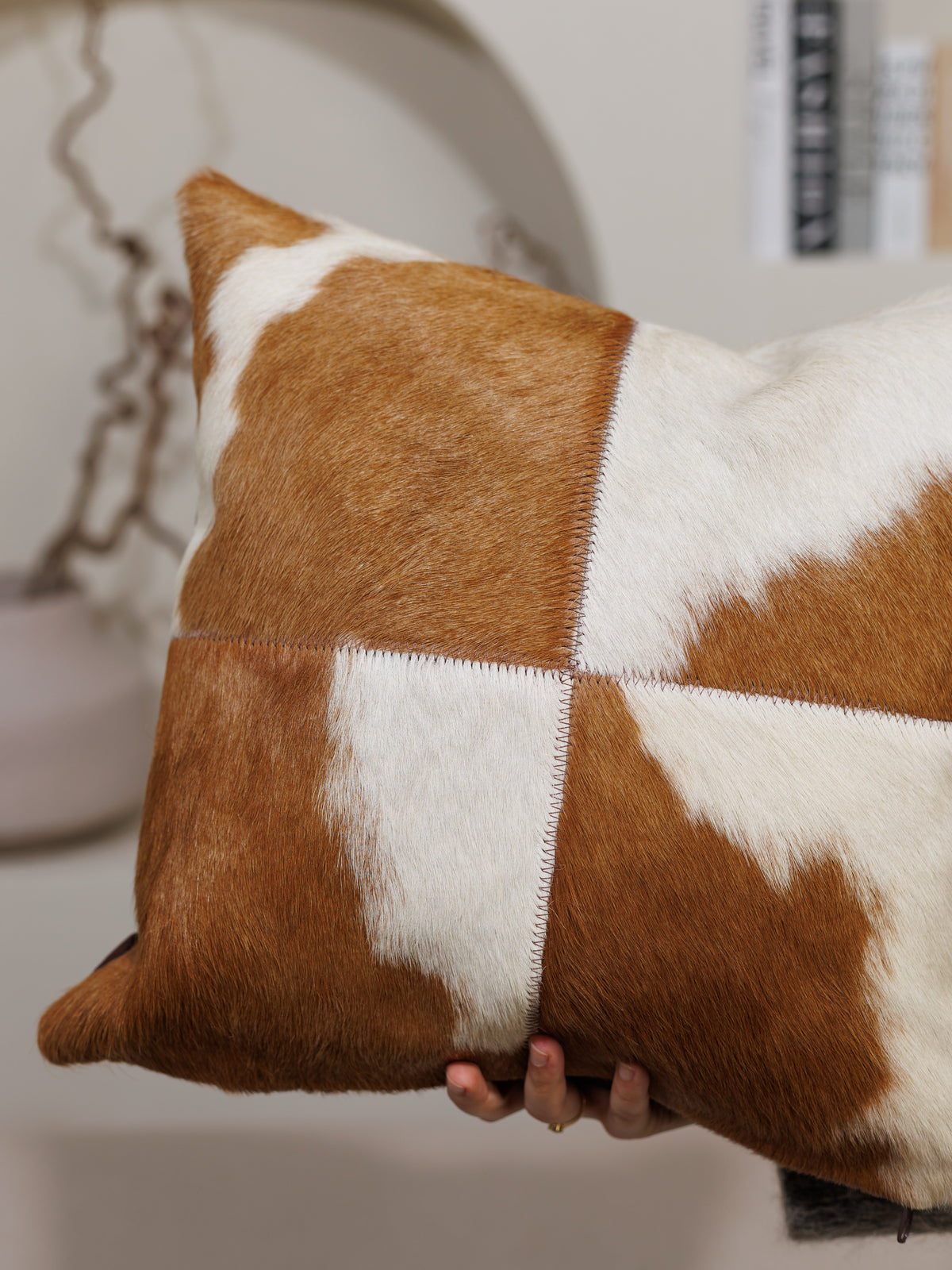 Housse de coussin en peau de vache marron et blanc, tenue en main