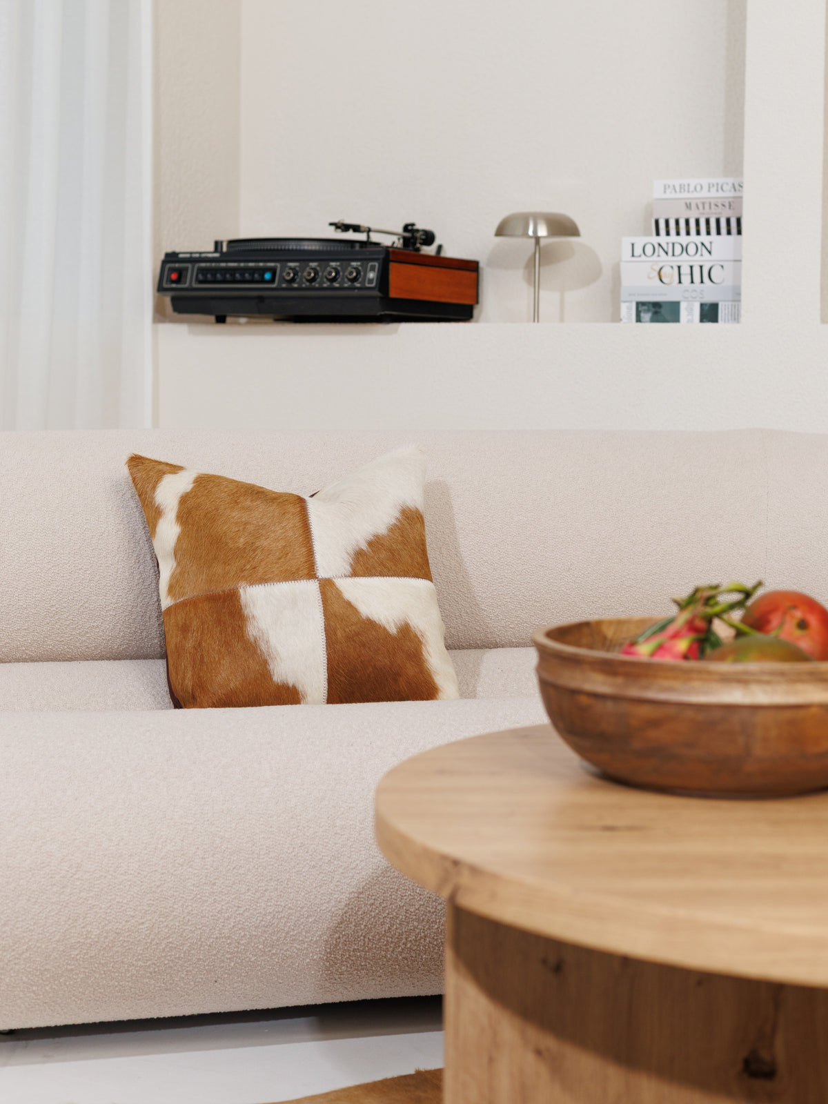 Housse de coussin en peau de vache marron et blanc sur un canapé clair