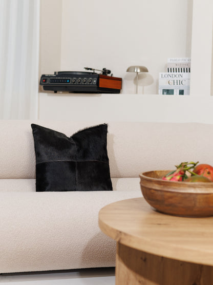 Housse de coussin en peau de vache noire sur un canapé clair